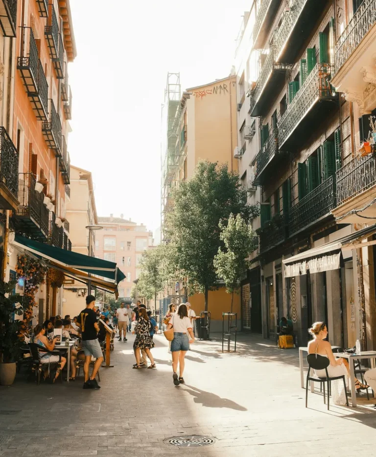 Personas paseando por una calle con terrazas en el barrio de Malasaña, Madrid