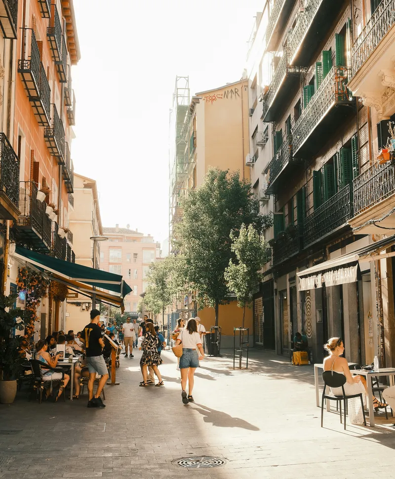 Personas paseando por una calle con terrazas en el barrio de Malasaña, Madrid