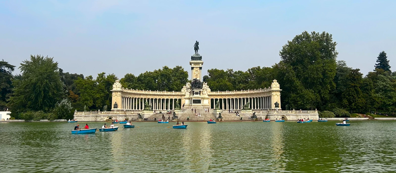 Personas navegando en barcas por el estanque del Parque del Retiro, frente al monumento a Alfonso XII en Madrid
