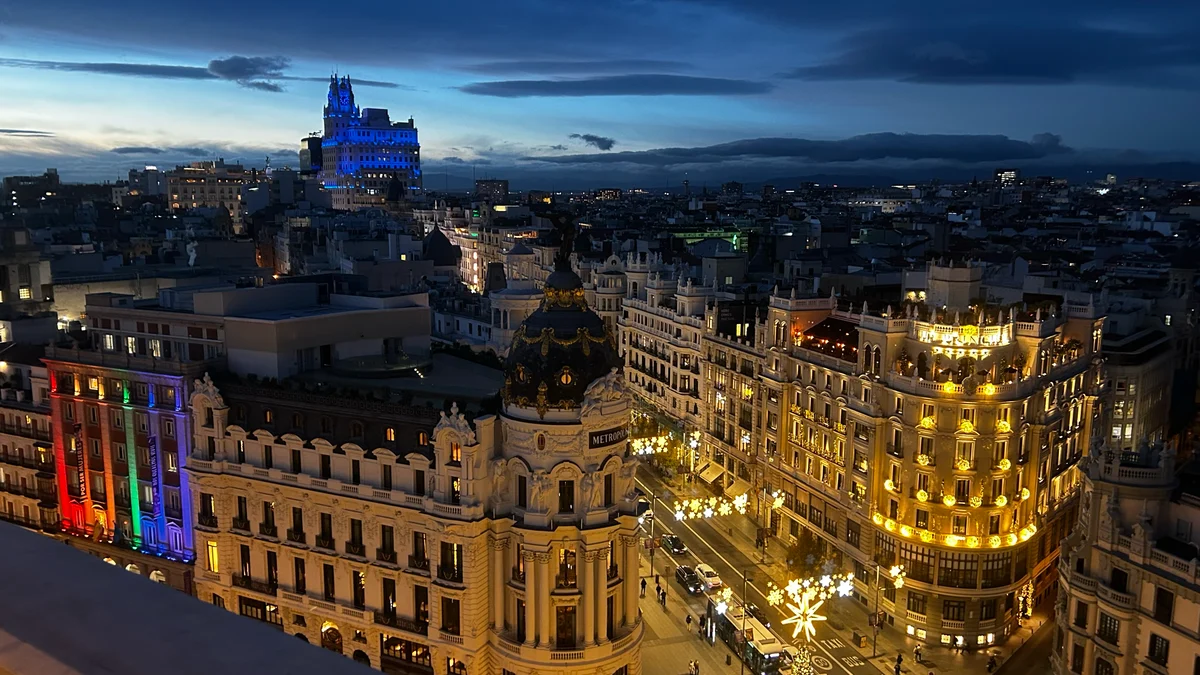 Vista nocturna de Gran Vía y el Edificio Metrópolis desde la azotea del Círculo de Bellas Artes iluminados al anochecer.