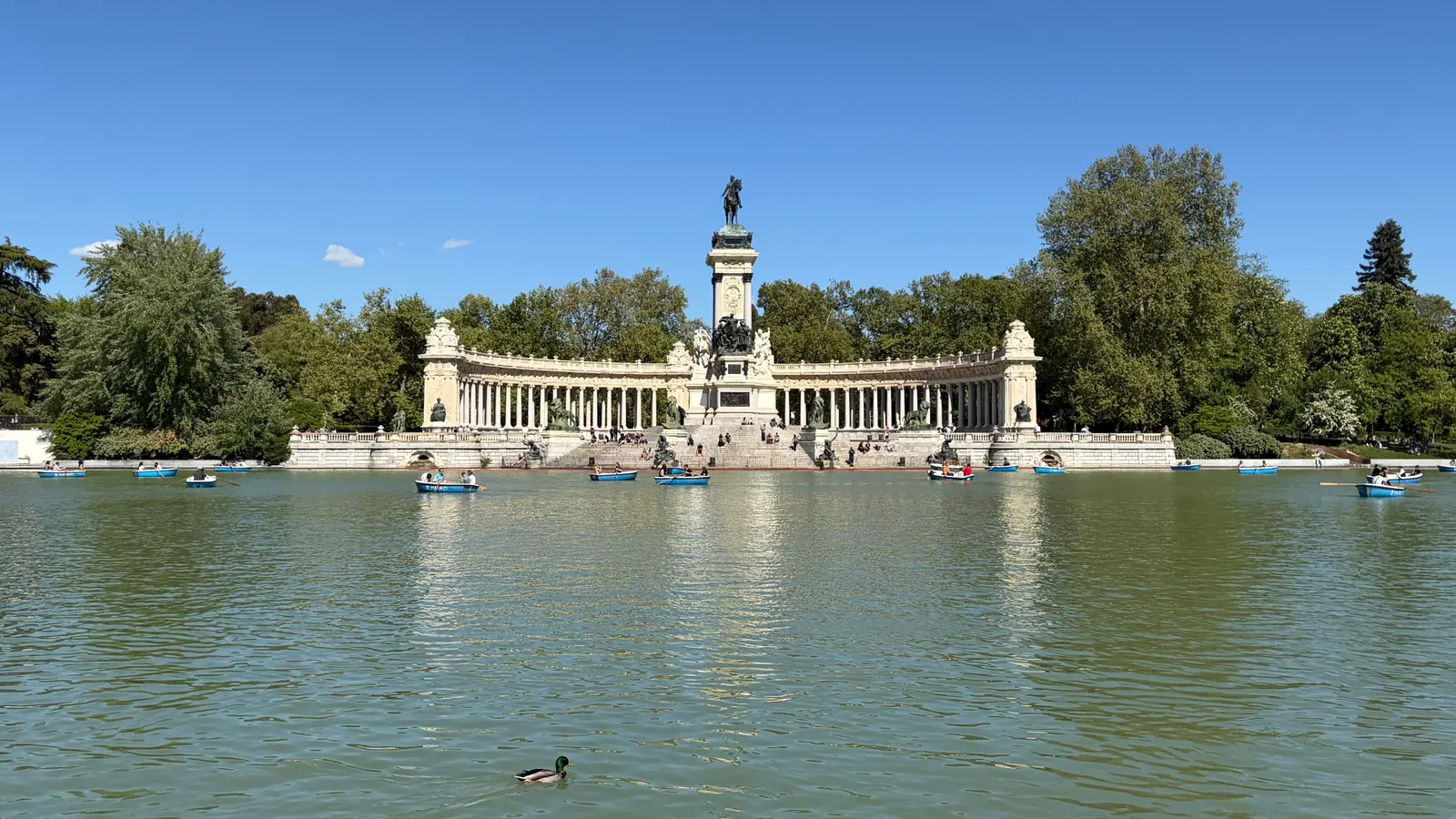 Monumento a Alfonso XII seen from across the Estanque Grande, with rowing boats on the water, in Parque del Retiro, Madrid.