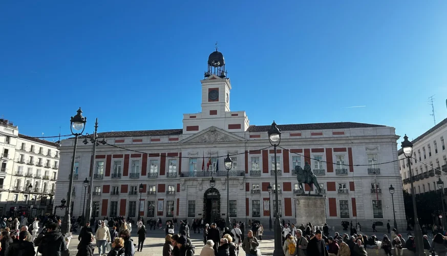 Real Casa de Correos on Puerta del Sol seen frontally with the clock tower, the equestrian statue and crowds in the plaza, Madrid