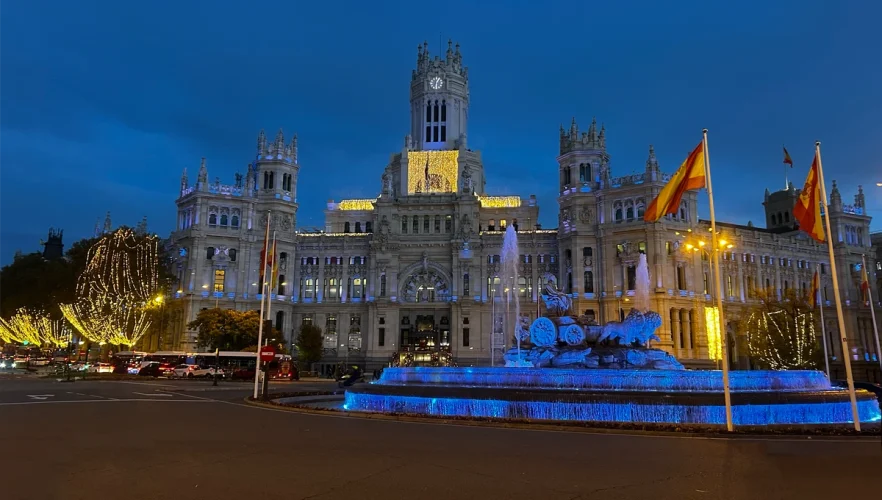 Fuente y Palacio de Cibeles iluminados de noche en Madrid.