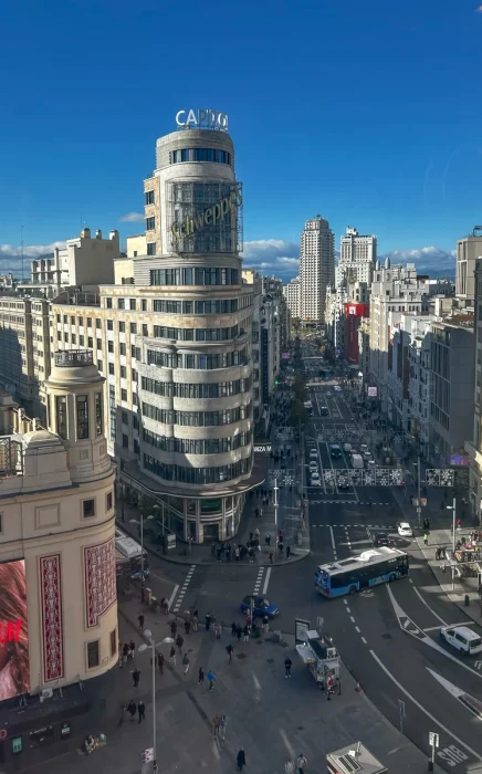 Vista del Edificio Capitol y el cartel de Schweppes desde la plaza de Callao en una tarde clara.
