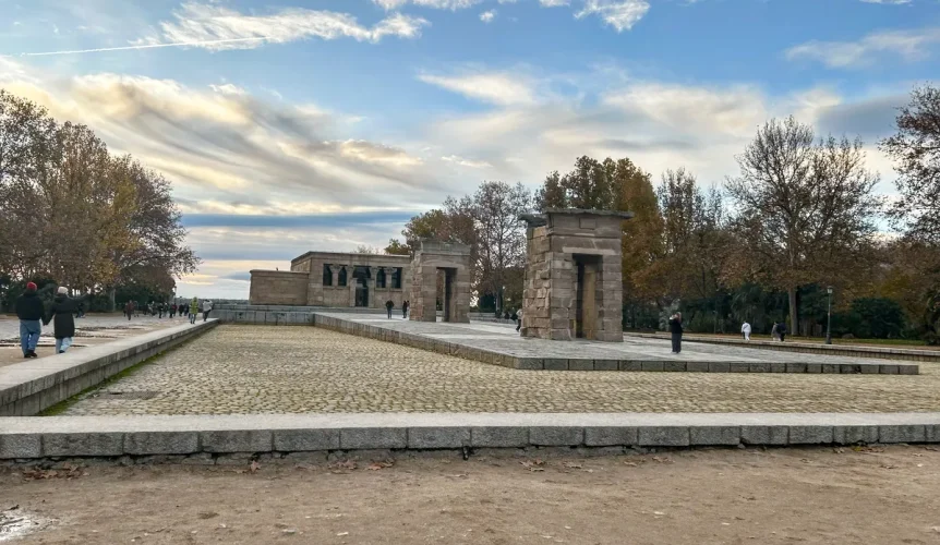 Vista del Templo de Debod en Madrid durante la tarde, con sus estructuras de piedra y el cielo parcialmente nublado.