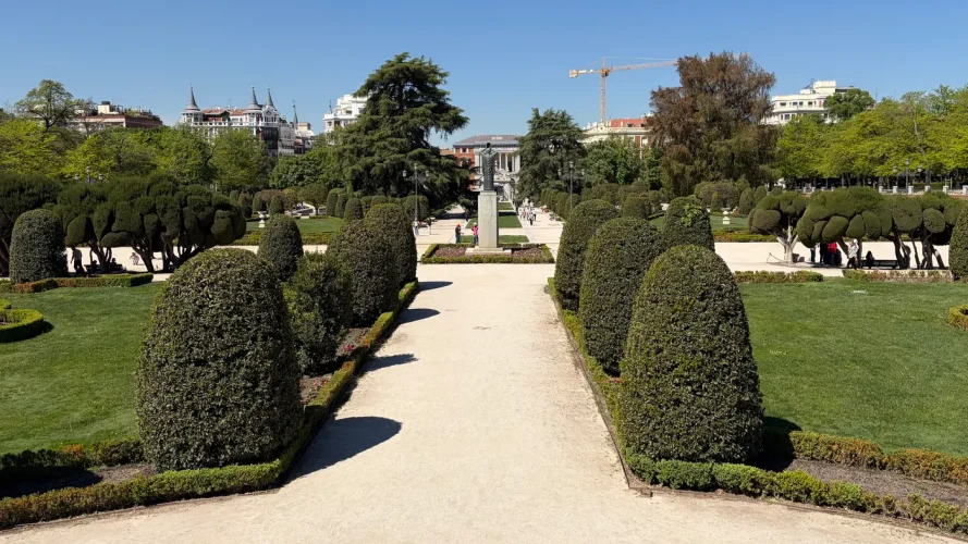 View of El Parterre in Parque del Retiro, Madrid, with topiary hedges and geometric paths, and the ahuehuete tree visible on the right.
