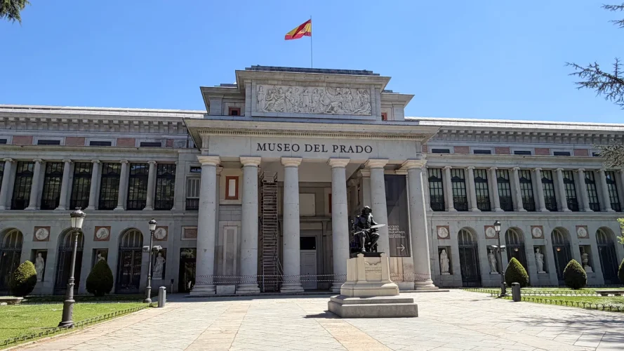 The main façade of the Museo del Prado with its neoclassical columns, the pediment frieze, and the statue of Velázquez in front, in Madrid.